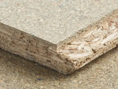 Close-up of a textured particle board showing layers of compressed wood chips and fibers on a flat surface.